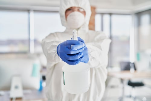 Urgent Extreme Cleaners technician in full protective gear preparing a sanitization treatment